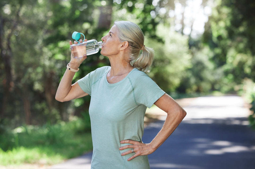 Woman taking a walk and drinking water for healthy aging and wellness